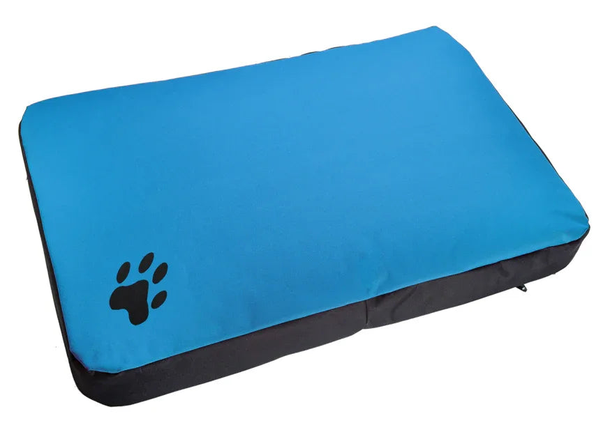 Cama rectangular para perro color turquesa, resistente y con huella negra en una esquina.
